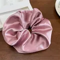 Détail d'un grand chouchou en satin rose avec éclat soyeux sur une table en bois - Rose rosé