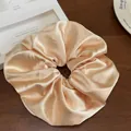 Gros plan sur le chouchou en satin doré champagne avec texture soyeuse et éclat - Crème