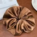 Vue détaillée d'un grand chouchou en satin marron avec texture plissée brillante sur bois - Café Mocha