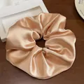 Gros plan du chouchou en satin doré champagne avec une texture plissée élégante sur bois - Champagne
