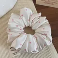 Dettaglio di elastico scrunchie in raso crema a pois rosa con etichetta in tessuto - Bianco Sporco