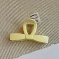 Detail view of cream yellow bow-shaped hair claw clip with a glossy finish - Yellow Bow