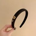 Eleganter gepolsterter Haarreif aus schwarzem Samt mit goldener Kamelie und Logo-Detail - Schwarz