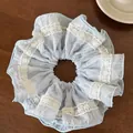 Detail of light blue lace scrunchie with pink polka dots and floral embroidery on wood - Blue