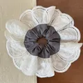 Macro detail of oversized white lace floral embroidery on dark grey elastic scrunchie - Gray