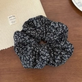 Detailed texture of black and white floral fabric scrunchie on wooden background - Black Floral