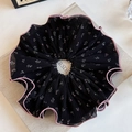 Detail eines Blumen-Scrunchies mit schwarzem Chiffon und rosa gewellten Rändern - Schwarzes Falten-Haargummi