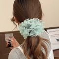 Detail of light green lace scrunchie with polka dots shown on model's ponytail - Green