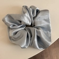 Close-up of glossy silver-grey satin scrunchie with elegant silk-like pleated texture - Blue
