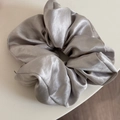 Detailed view of silver grey satin silk scrunchie with soft pleated texture and elegant shine - Gray