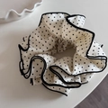 Detail van grote zwart-witte stippen scrunchie met gelaagde golvende randen en textuur - Melkwit