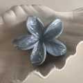 Makro-Detail der blau-weiß marmorierten Haarklammer in Form einer Frangipani-Blüte - Nebelblau