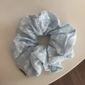 Close-up of light blue floral scrunchie with gingham patterns and a white brand label - Large Floral Grid Style (FQ881456) / Blue