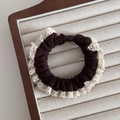 Close-up of coffee brown scrunchie with cream lace edges on a wooden display tray - Brown