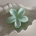 Macro detail of mint green frangipani hair claw with pearlescent marble texture - Green