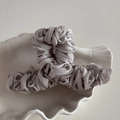 Detail view of silver-grey pleated fabric wrapped on a square hollow hair claw clip - Gray