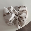 Detailed close-up of a floral satin scrunchie featuring a smooth glossy texture and pleats - Beige Print Scrunchie