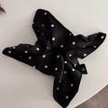 Close-up of black floral satin scrunchie with white flower print and woven brand label - Black Print Ribbon Scrunchie