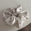 Nahaufnahme von Satin-Haargummi mit filigranem schwarzem Blumenmuster auf Beige - Weißer Aufdruck Scrunchie
