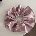 Detailed view of pink satin scrunchie with silk bows and a silver brand tag - Pink