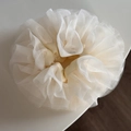 Dettaglio macro dell'elastico per capelli in rete bianco latte con volant a strati - Beige