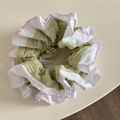 Détail d'un chouchou plissé vert clair et blanc avec une broderie rose décorative - Style Bord Festonné Vert