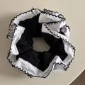 Detail eines schwarzen Haargummis mit weißen Wellenkanten und Kontrastnähten im Design - Schwarzer Wellenkanten-Stil