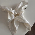Detailed view of cream satin scrunchie with pearl luster and branded woven label - Off White