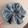 Dettaglio di scrunchie in denim a fiori blu con motivi bianchi ed etichetta Andrea - Scrunchie plissettati / Azzurro