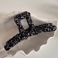Gros plan d'une pince à cheveux élégante en tissu floral sur un plateau en coquillage - Noir Floral Droit