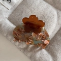 Macro detail of amber flower hair claw with vintage tortoiseshell texture and polished finish - Green & Brown