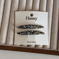 Detail view of two French style acetate hair clips with leopard print and gold accents - Black and White