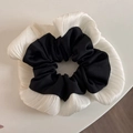 Λεπτομερής προβολή του δίχρωμου σατέν scrunchie με ασπρόμαυρες πτυχώσεις και βολάν - Μαύρο