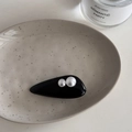 Detail view of a glossy black hair clip with pearl embellishments on a ceramic tray - Black French Pearl - Waterdrop Clip