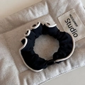 Λεπτομέρεια μαύρου scrunchie με λευκή πέρλα σε μαλακό καπιτονέ φόντο για μαλλιά - Βασικό Μαύρο Στυλ