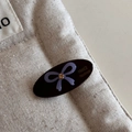 Detailed macro view of an oval black resin hair clip with purple bow and sparkling crystal - Dark Brown