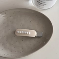 Detailed close-up of a French style cream hair clip with white pearls on a ceramic tray - White French Pearl - Rectangular Clip