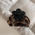 Tortoiseshell acetate hair claw clip with a black flower accent on rustic linen background - Tortoise