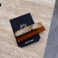 Dettaglio set di due fermagli in acetato marmo beige e marrone caramello su cartoncino - Marrone Arancio