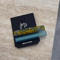 Detail of two handmade acetate hair clips with marble patterns on a black display card - Blue