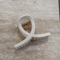 Détail d'une grande pince à cheveux blanc crème avec ressort doré sur surface en marbre - Crème Unie - Forme en X