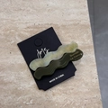 Dettaglio di fermagli per capelli ondulati in acetato verde chiaro e scuro su carta - Verde