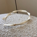 Detalle de la textura de tela beige y la placa metálica dorada en la diadema fina - Blanco