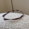 Detalle de la diadema de tela de seda color púrpura oscuro con una placa de metal dorada - Morado