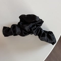 Détail d'une pince à cheveux en satin noir avec texture plissée et éclat soyeux élégant - Pince à Cheveux Noire