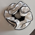 Détail de la pince à cheveux en satin plissé crème avec bord noir et étiquette mode - Chouchou Blanc