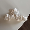 Vue détaillée d'une pince à cheveux en satin plissé de couleur crème sur fond blanc - Pince crabe blanche