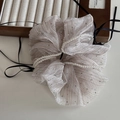 Dettaglio di uno scrunchie in organza champagne con perle bianche e lunghi nastri neri - Beige