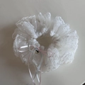 Close-up of white lace scrunchie with polka dots, pink ribbons and a gold heart pendant - Beige