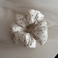 Detail of soft cream satin scrunchie with black polka dots and pleated fabric texture - Off White